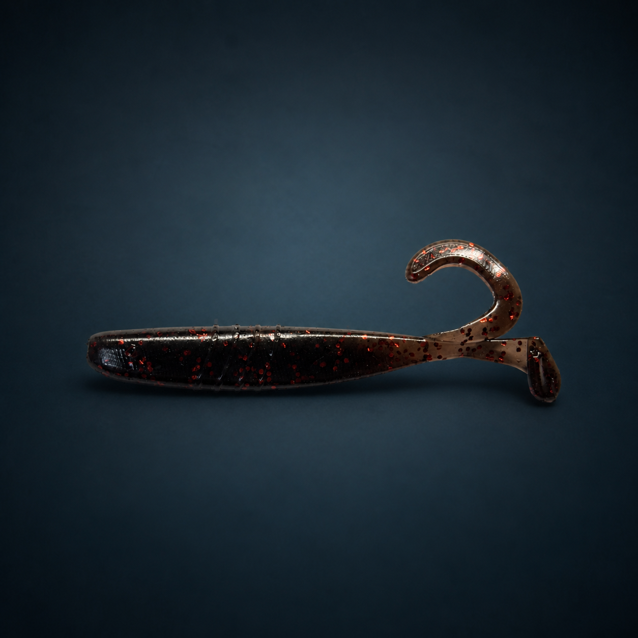 Mudcraw black-brown soft plastic fishing lure with red glitter on dark blue